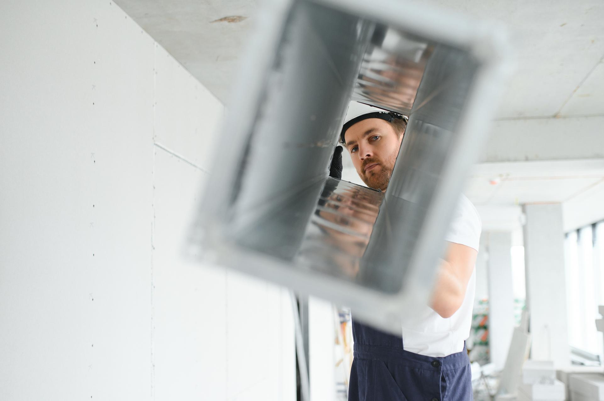 Industrial Theme. Warehouse Heating and Cooling System Installation by Professional Caucasian Technician. Commercial Building Ventilation Rectangle Canals. Air Distribution.