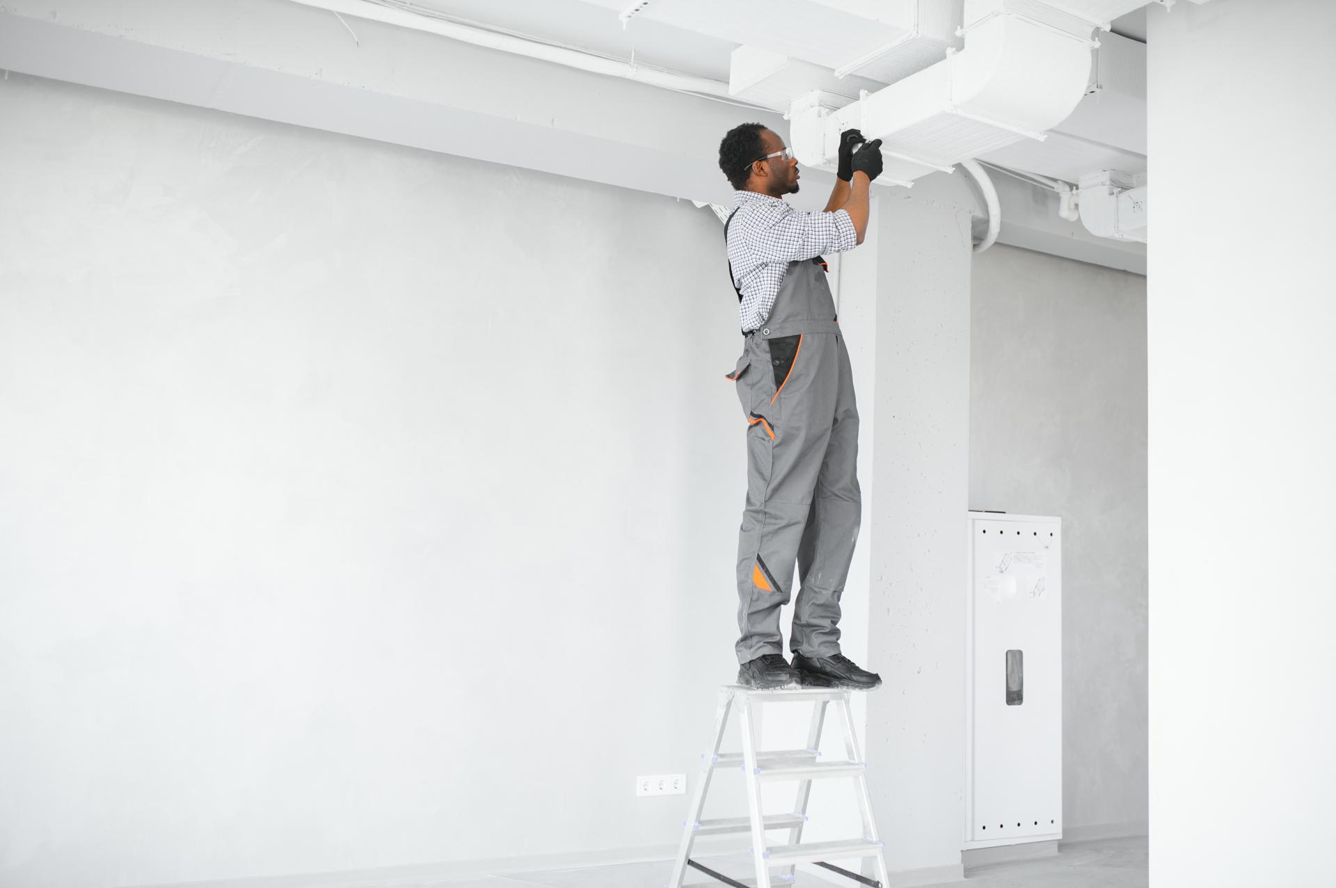 African HVAC Technician Worker Testing Newly Installed Ventilation System. Commercial Heating, Cooling and Air Ventilation Systems